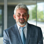 Suat G. Karakus, üzletember portréja öltönyben, mosolygós férfi irodai környezetben